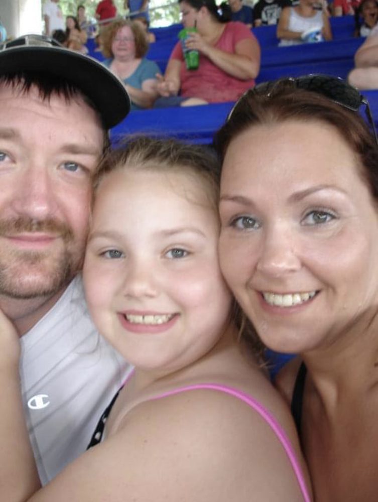Marissa as a child, smiling with two family members