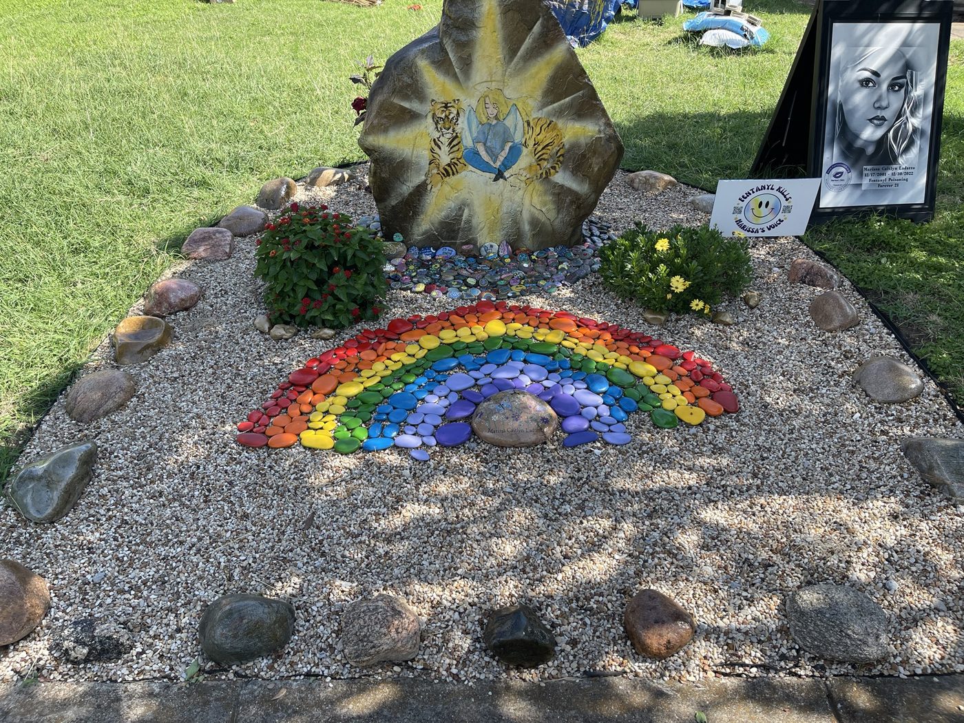 The painted boulder of Marissa as an angel with tigers, above the painted rocks and rainbow