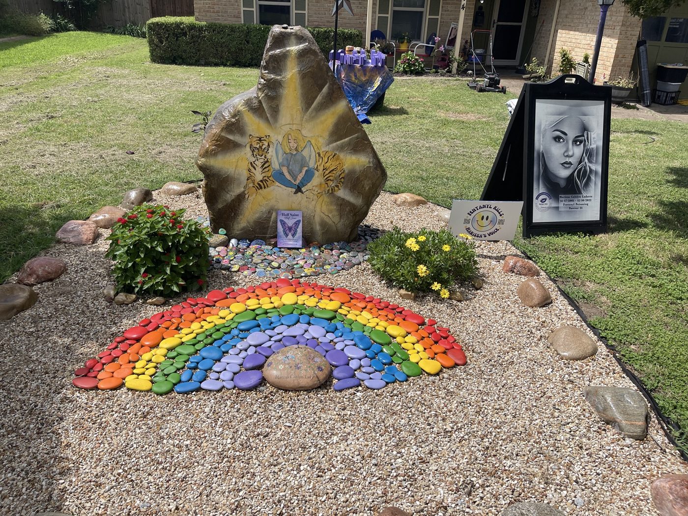 The memorial rock garden with the painted boulder, rainbow of stones and Marissa’s portrait
