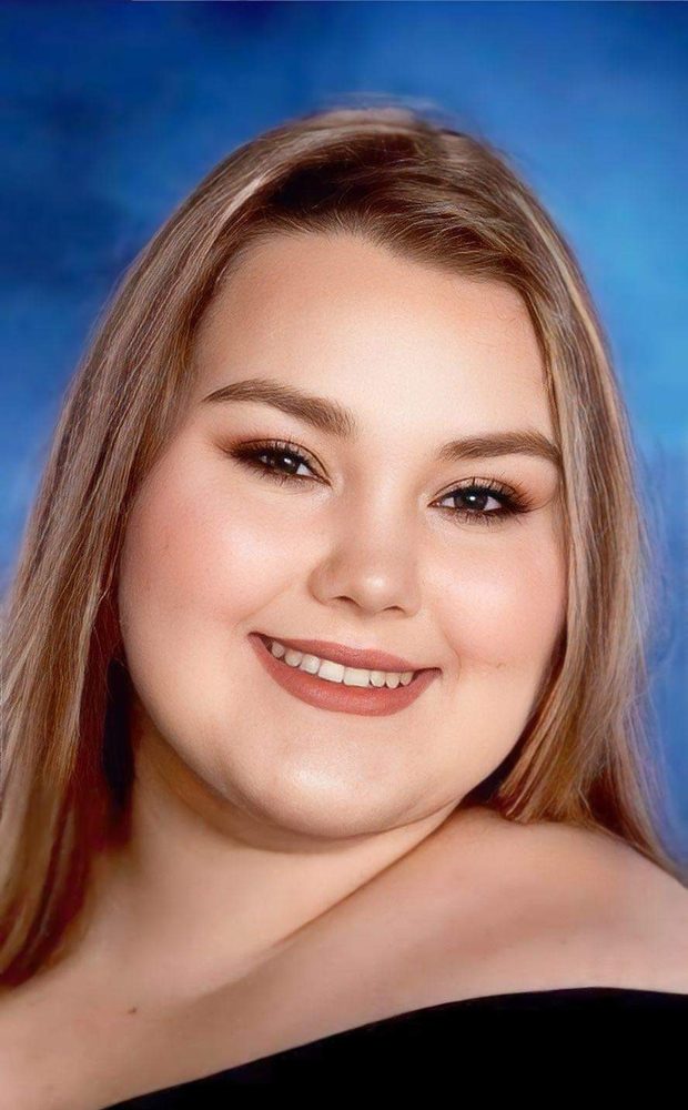 Marissa’s senior portrait against a blue backdrop
