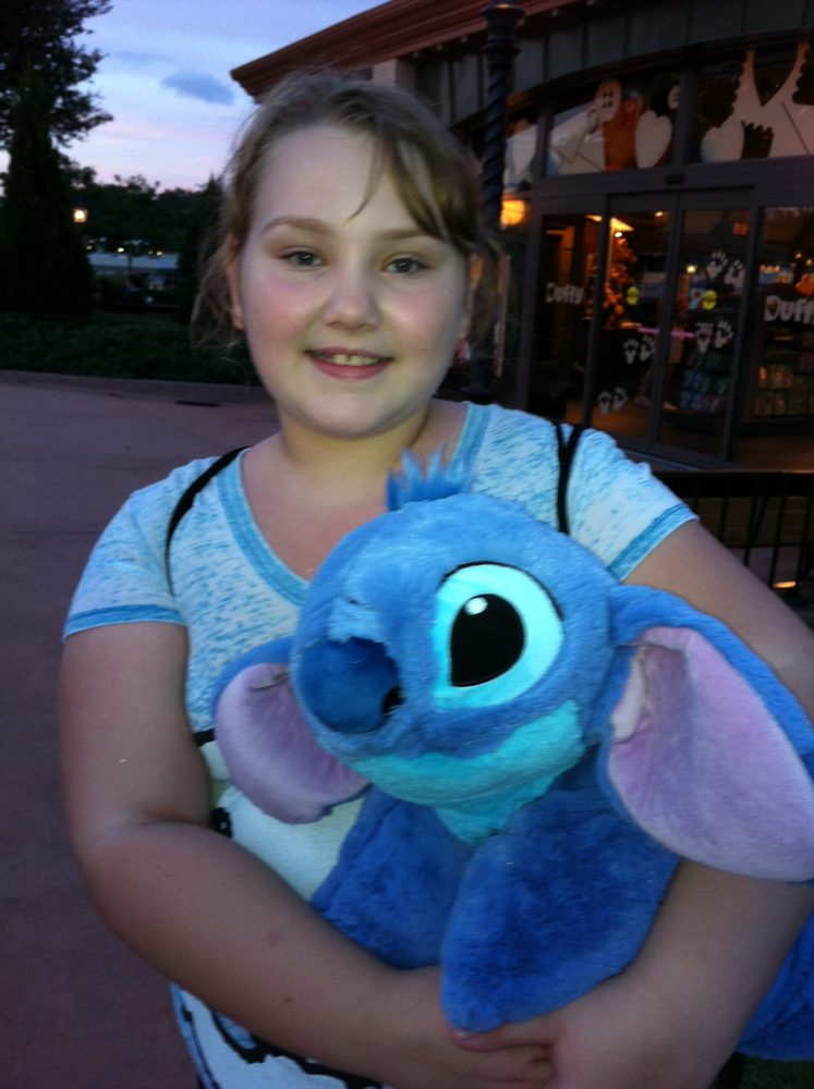 Young Marissa holding a Stitch plush toy